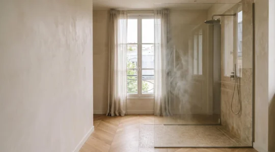 Vaste espace douche vitré baigné de lumière naturelle dans une salle de bain épurée à la française
