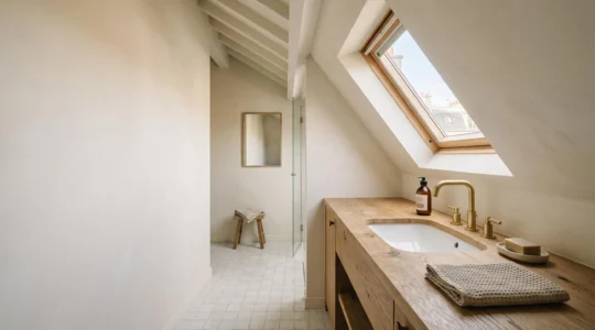 Vasque sur plan de toilette en bois massif installée sous une pente de toit dans une salle de bain mansardée lumineuse